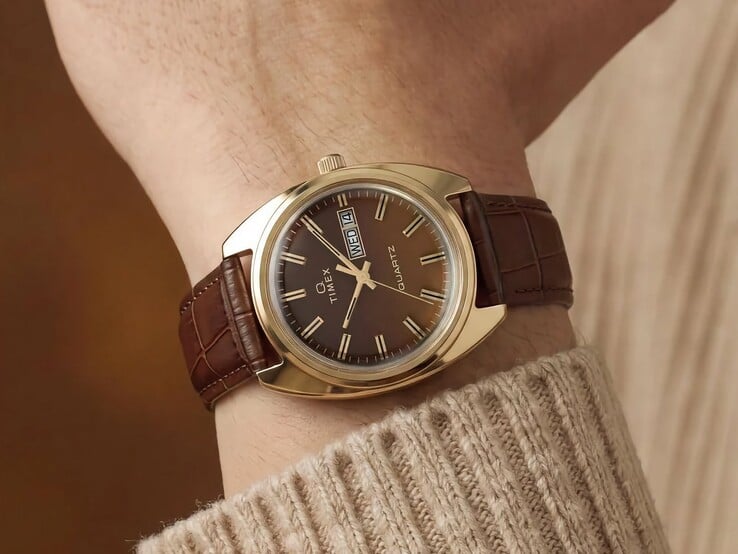 Timex Q 1976 Day and Date，配有棕色烟熏渐变表盘和金色表壳，搭配棕色皮革表带，佩戴于手腕上。
