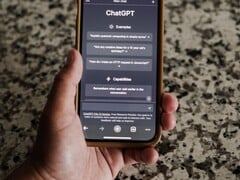 一只手拿着智能手机，屏幕上显示着ChatGPT界面
