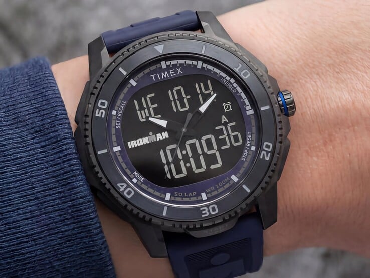 一款黑色 Timex Ironman Adrenaline 模拟数字双显示手表,配有深蓝色表带和蓝色表冠装饰,图中展示于手腕上。