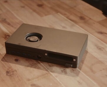 一台紧凑型黑色游戏主机,内置光驱、USB接口和顶部散热风扇,静静地置于木桌上。