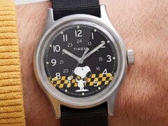 Timex MK1黑色表盘的特写镜头，表盘上以黄黑格纹为背景印有史努比图案，配有阿拉伯数字时标和夜光指针。