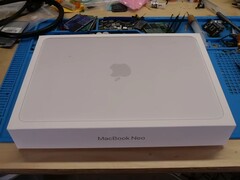 MacBook Neo 零售包装盒拆卸前放置在工作台上,以便升级固态硬盘
