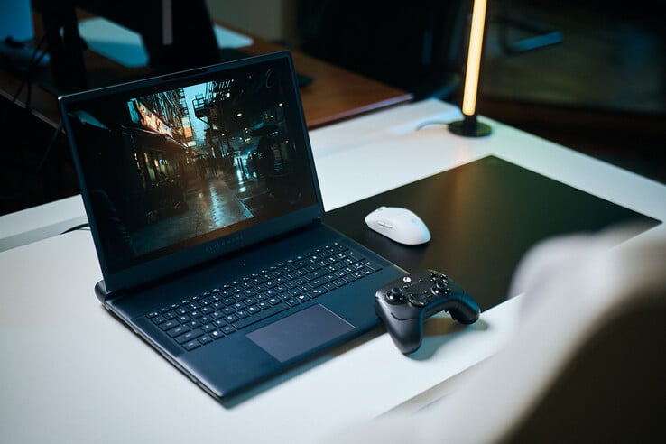 一台打开的Alienware游戏笔记本电脑摆放在白色工作室桌面上，正在运行一幅黑暗且具有镜面反射效果的街景画面，画面细节清晰锐利，采用了路径追踪技术呈现，配以黑色手柄和白色无线鼠标。