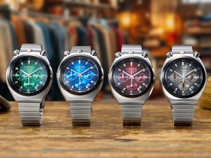 四款 Citizen Tsuno Chronograph 腕表并排摆放在木质表面上，表盘分别呈绿色、蓝色、红色和灰色渐变，采用不锈钢材质