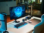 一套简洁的studio游戏配置：白色桌面上摆放着索尼Inzone M10S II显示器，旁边是竖置的PlayStation 5 Pro主机、机械键盘、无线鼠标以及带有淡蓝色背光的耳机。
