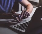 在微弱的光线下,一双双手正在MacBook键盘上敲击,苹果标志正发出微光