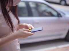 一名女子正在智能手机上打字，背景中有一辆银色汽车