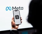 一只手握着智能手机,手机位于一个巨大的 Meta 标志前方