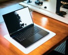 一台深黑色Razer Blade 16游戏笔记本电脑,置于白色桌垫上,桌垫下是温暖的木质桌面,屏幕上显示着一幅生动鲜明的黑白壁纸。