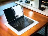 一台深黑色Razer Blade 16游戏笔记本电脑，置于白色桌垫上，桌垫下是温暖的木质桌面，屏幕上显示着一幅生动鲜明的黑白壁纸。