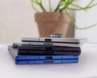 代表即将推出的Apple iPhone Fold 概念的可折叠智能手机堆放在一张白色桌子上，背景是一盆植物（图片来源：Notebookcheck）