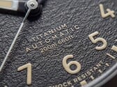 Timex Expedition Field Post Titanium 腕表的特写镜头，展现其带有阿拉伯数字的纹理黑色表盘、夜光指针和时标，以及日期窗口。
