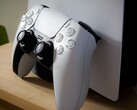 一张 PlayStation 5 DualSense 控制器斜靠在 PS5 主机上的图片