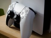 一张 PlayStation 5 DualSense 控制器斜靠在 PS5 主机上的图片