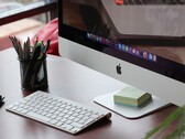桌面上放着一台iMac，屏幕上显示着macOS的Dock栏，前方摆放着一台Apple键盘