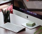 桌面上放着一台iMac，屏幕上显示着macOS的Dock栏，前方摆放着一台Apple键盘