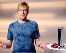 马克-切尼（Mark Cerny）在一次 PlayStation 活动中，坐在 PS5 游戏机和 DualSense 控制器旁。(图片来源：索尼互动娱乐公司）