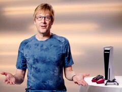 马克-切尼（Mark Cerny）在一次 PlayStation 活动中，坐在 PS5 游戏机和 DualSense 控制器旁。(图片来源：索尼互动娱乐公司）