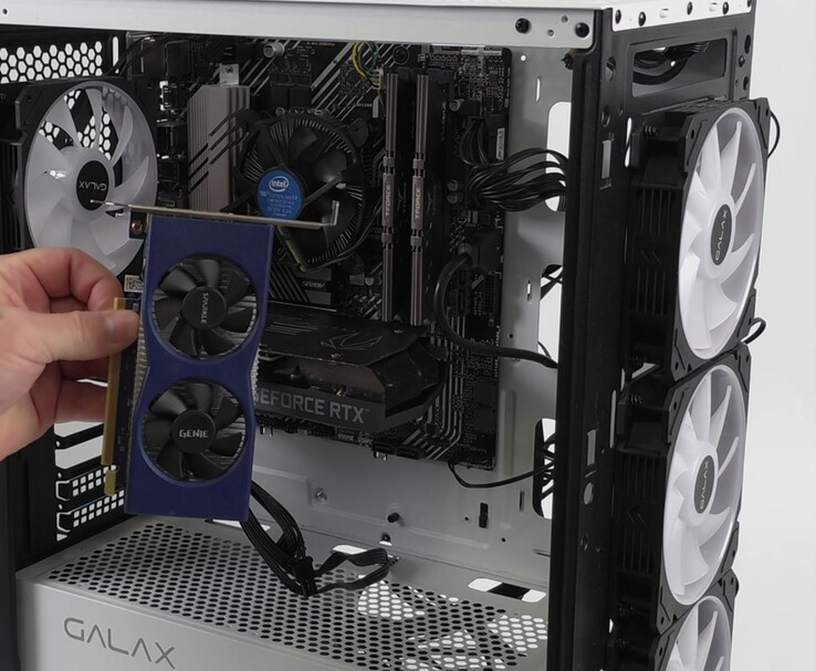 一只手拿着英特尔 Arc A380 显卡，旁边是一台配备 NvidiaGeForce RTX 3060 的 PC，准备使用无损缩放的双 GPU 设置（图片来源：ETA PRIME via YouTube）
