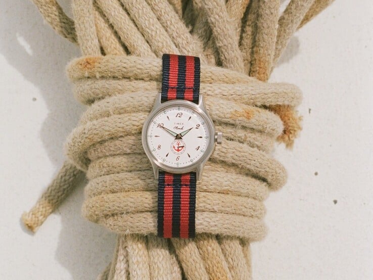 Noah x Timex MK1 Anchor 腕表，配有银色调 36 毫米表壳、白色表盘、锚形图案以及海军蓝与红色条纹织物表带。