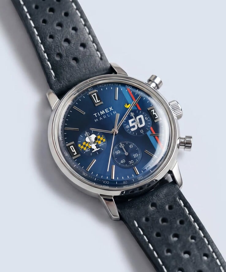 Timex Peanuts x Marlin 计时码表以倾斜角度呈现，其抛光不锈钢表壳、蓝色太阳纹表盘以及带镂空设计的蓝色皮革表带一览无余。