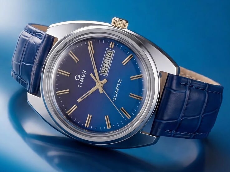 Timex Q 1976 Day and Date 的斜角产品照，突出展示其蓝色渐变表盘、抛光不锈钢表壳和金色表冠。