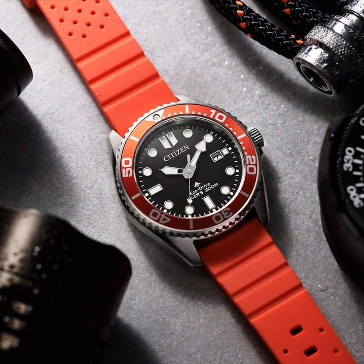 Citizen Promaster Marine BN0268-01E 潜水表,配有黑色表盘、橙色表圈和橙色表带,拍摄于带有纹理的表面上。