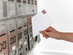 一只手将信封放入一排信箱中