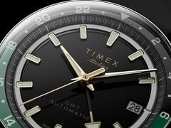 Timex Atelier GMT Première M1a 黑色表盘特写,配有金色指针、夜光时标、日期窗,以及黑绿双色 24 小时 GMT 表圈。