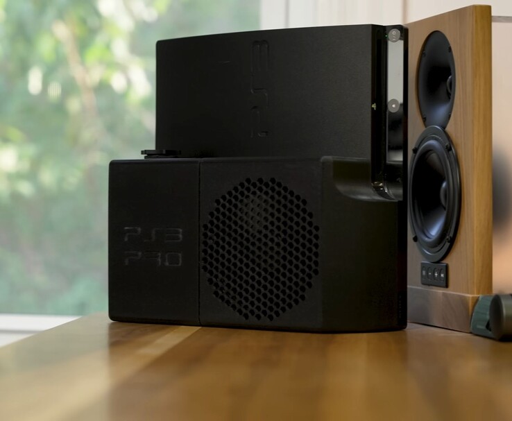 带黑色 3D 打印 "PS3 Pro "后壳的水冷式 PlayStation 3,旁边是一个木制扬声器。(图片来源:Zac Builds via YouTube)