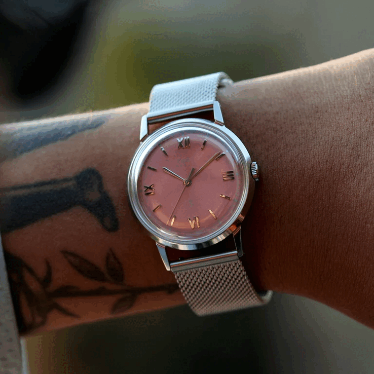 佩戴Timex x Todd Snyder Marlin Mesh腕表的人,该表款配有鲑鱼色太阳纹表盘和网状表链。