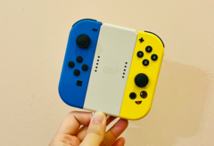 图片。一只手拿着 Joy-Cons （图片来源：Gwen King on Unsplash）