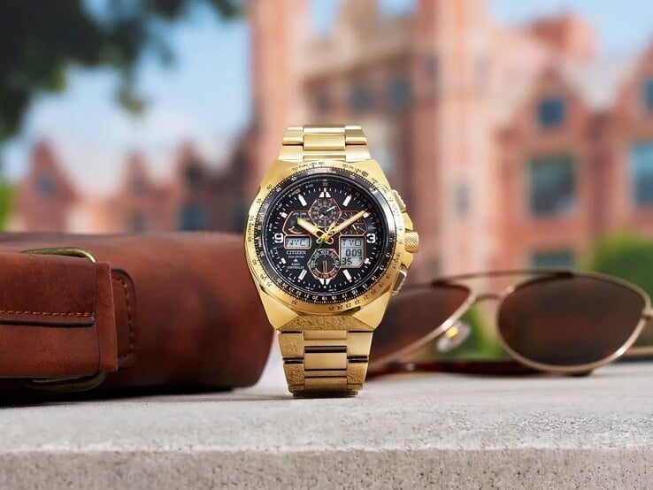 Citizen Promaster Skyhawk A-T JY8144-50E 金色调飞行员腕表直立陈列在窗台边缘,旁边放着一个棕色皮包和一副太阳镜,背景中是一幅模糊的城市天际线。