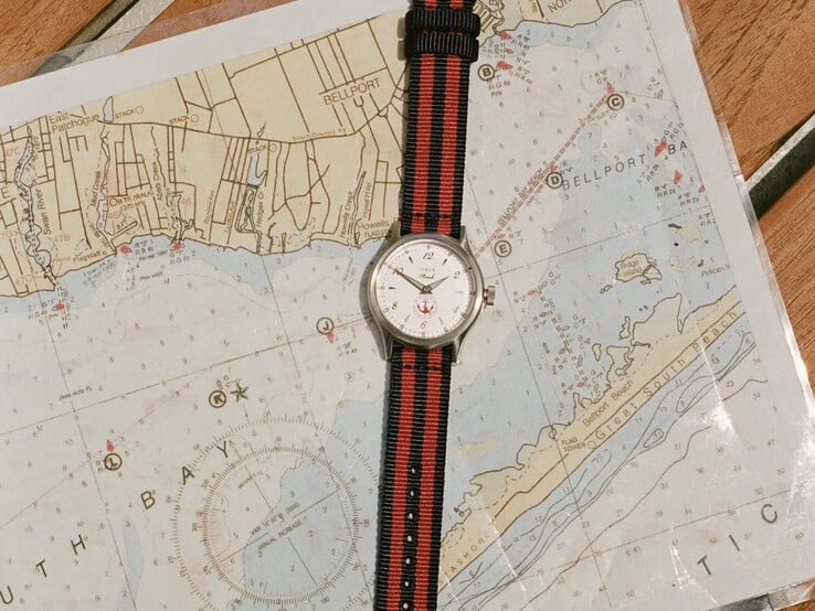 Noah x Timex MK1 Anchor 腕表，配有海军蓝与红色条纹织物表带，置于海图之上。