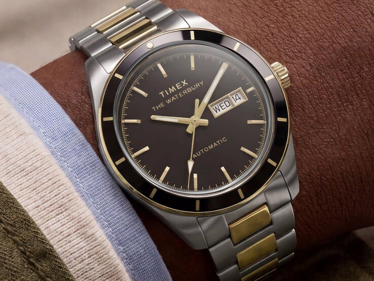 一只双色调的Timex Waterbury Heritage自动腕表,配有黑色表盘,佩戴在手腕上,显示着星期和日期,并带有金色调的装饰细节。