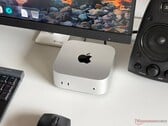 一台搭载 Apple M6 处理器的 Mac mini 置于游戏设置的桌面上，配有显示器、键盘、鼠标和扬声器。