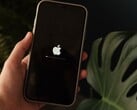 一只手握着一部iPhone,屏幕上显示着苹果标志和进度条。