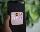 一只手拿着一部智能手机，屏幕上显示着一个名为“AI”的文件夹，其中包含 Gemini、ChatGPT 和 Claude 等应用程序
