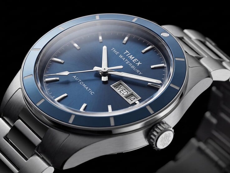 Timex Waterbury Heritage Automatic 蓝盘腕表的特写镜头,展示了其夜光指针、镶嵌式时标以及星期-日期显示窗。