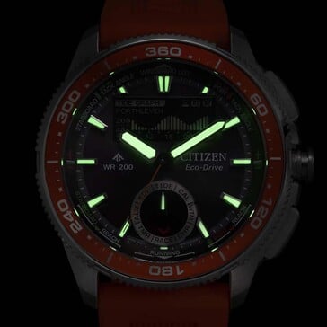 Low-light lume shot of the Citizen Promaster Wave Tracker JV3000-13E showing glowing hands and hour markers against a dark background.