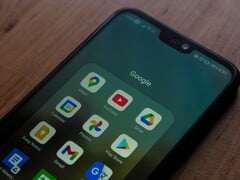 放在木质桌上的智能手机,屏幕上显示着已打开的 Google 应用文件夹