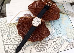 金色 Noah × Timex Boatswain 腕表,配有白色罗马数字表盘和黑色皮革表带,置于航海图和编织藤条上拍摄。