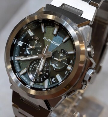 卡西欧G-Shock GST-W1000D-3A绿色表盘的特写镜头,展示了其几何纹理表盘、三个小表盘、夜光刻度以及抛光不锈钢表圈。