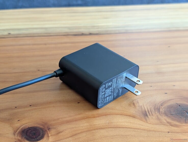 随联想 Yoga Slim 7 14 附赠的 65 W USB-C 交流适配器。请注意其不可伸缩的交流插头，以及另一端集成的 USB-C 数据线