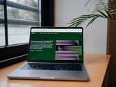 一台笔记本电脑放在窗边的桌子上，屏幕上显示着OpenAI ChatGPT网站