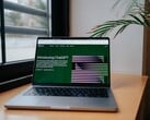 一台笔记本电脑放在窗边的桌子上,屏幕上显示着OpenAI ChatGPT网站