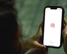 一名女子双手捧着智能手机，屏幕上显示的是 Instagram 的首页