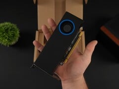 手持配备鼓风机式散热器的英特尔 Arc Pro B50 低配置工作站 GPU 的人，与包装盒对比。(图片来源：ETA Prime via YouTube）