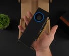 手持配备鼓风机式散热器的英特尔 Arc Pro B50 低配置工作站 GPU 的人，与包装盒对比。(图片来源：ETA Prime via YouTube）